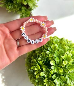 a woman's hand holding a beaded name bracelet