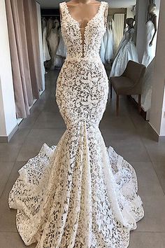 a white wedding dress on display in front of mannequins and other dresses