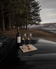 two wine glasses sitting on top of a black car