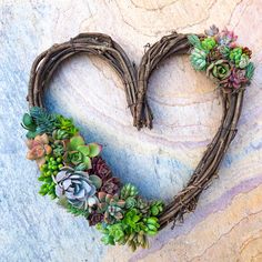 a heart shaped wreath with succulents on it