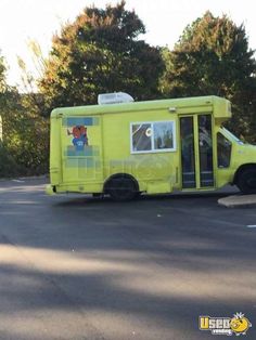 a yellow food truck is parked on the side of the road with trees in the background