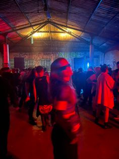 a group of people standing around in a room with red lights on the ceiling and walls