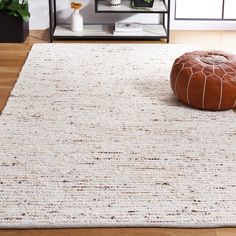 a white rug on the floor with a brown pouffle sitting next to it