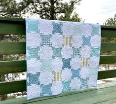 a blue and white quilt hanging on a wooden fence