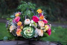 an arrangement of flowers on top of a wooden bench