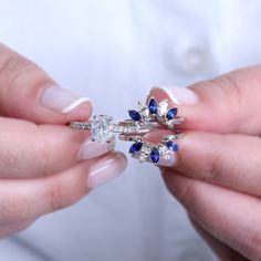 a woman holding two rings with blue and white stones