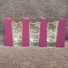 three shot glasses with hello kitty etched on the front and sides, sitting on a carpeted area