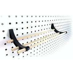 a pair of black and white hooks on a pegboard with holes in the background