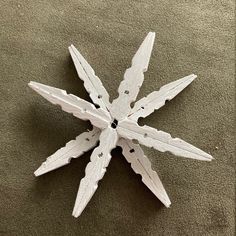 a snowflake made out of white wood on a carpeted floor with no one around it