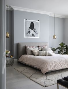 a bedroom with grey walls and light pink bedding in the corner, along with potted plants