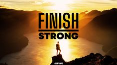 a man standing on top of a mountain with the words finish strong in front of him