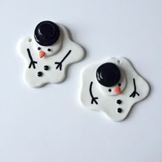 two ceramic snowmen with black hats and noses