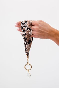 a hand holding a key chain with a snake skin pattern on it and a ring hanging from the end