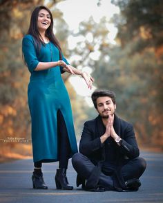 a man kneeling down next to a woman in a blue dress and black shoes on the street