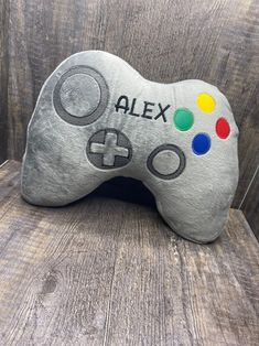 a pillow that says alex on it with a game controller in the middle of it