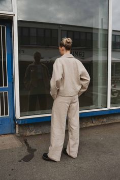 a woman standing in front of a store window with her back turned to the camera