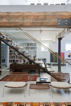 a living room filled with furniture and bookshelves next to a stair case full of books