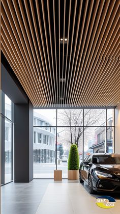 two black cars parked in front of a building with wooden slats on the ceiling