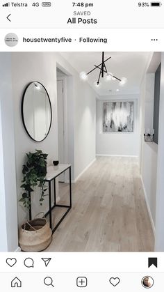 a white hallway with wood flooring and round mirrors