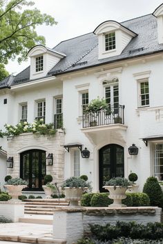 a large white house with lots of windows and plants on the balconies outside