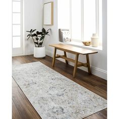 a large white rug in the corner of a room next to a wooden bench and window