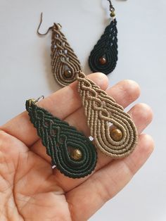 a pair of earrings is being held in someone's hand with other items nearby