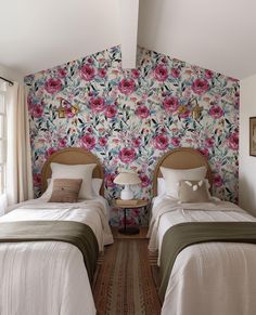 two beds in a room with floral wallpaper