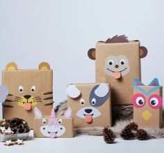 several cardboard boxes with animal faces on them and some pine cones in the foreground