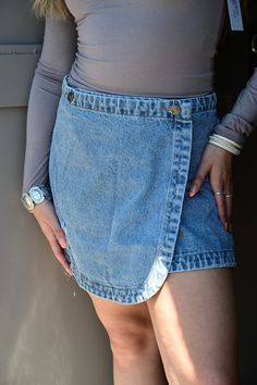 Stone washed denim mini skirt featuring a front wrap design with a button closure, slight distressing and a frayed bottom hem. Can be worn with a graphic tee and boots or a dressy blouse and sandals. Denim styled with #SJG8510 & SG6975Denim styled with #SG6975 Model is wearing a small. Fabric Contents100% COTTON Chic Medium Wash Skort For Summer, Chic Medium Wash Summer Skort, Summer Chic Medium Wash Skort, Medium Wash Denim Jean Shorts For Fall, Fall Medium Wash Denim Jean Shorts, Denim Mini Length Bottoms For Day Out, Denim Mini Bottoms For Day Out, Fall Denim Mini Skirt In Medium Wash, Frayed Hem Denim Jean Shorts For Fall