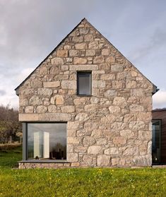 a stone house sitting on top of a lush green field