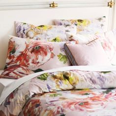 a bed with floral sheets and pillows on it