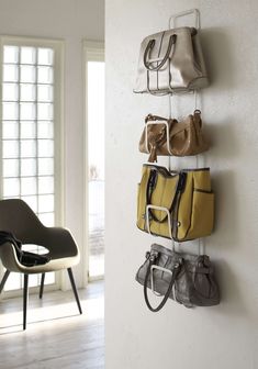 three purses hanging on the wall next to a chair