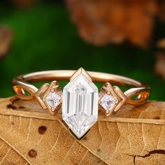 a close up of a diamond ring on top of a wooden surface with leaves in the background