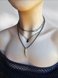 A black steel and 24 K gold filled steel Gothic Grunge alt aesthetic choker chain layered necklace set with heart and tusk pendants. The set is two separate necklaces that can be worn together or separate, one is a black steel horse eye paperclip chain choker with a built-in extender that runs from approximately 14" to 16". it also features a two strand necklace, one black steel with a gold filled tusk pendants and the other 24 K gold filled steel chain with a black heart charm. It is an adjustable length from approximately 16" to 18" with a built-in extender.  This necklace set is an excellent handmade gift for someone special. It is a perfect choice for those who love alternative and goth styles, as well as anyone who wants to make a statement with their jewelry. Punk Gold Stainless Steel Jewelry, Black Metal Jewelry With Chunky Chain, Edgy Black Chain Necklace For Gifts, Edgy Black Stainless Steel Necklace, Black Metal Clavicle Chain Charm Necklace, Black Metal Chain Necklace With Delicate Chain, Black Punk Clavicle Chain Necklace, Black Grunge Jewelry With Adjustable Chain, Black Delicate Chain Metal Necklace