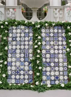 an outdoor wedding ceremony with blue and white tiles on the wall, flowers in the foreground