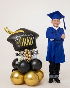 a boy in graduation cap and gown standing next to balloons that read congratulations grad