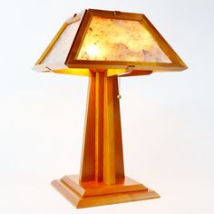 a lamp that is sitting on top of a wooden stand with a glass shade over it