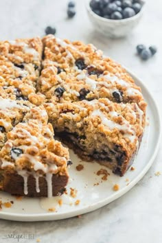 a blueberry crumb cake on a plate with one slice cut out and ready to be eaten