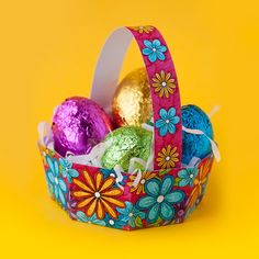 an easter basket filled with chocolate eggs on a yellow background and decorated with colorful flowers