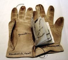 a pair of gloves with writing on the inside and outside of them, sitting on top of a sheet of paper