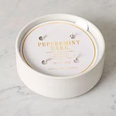 a white box with gold lettering on it sitting on a marble countertop next to a bottle of peppermint