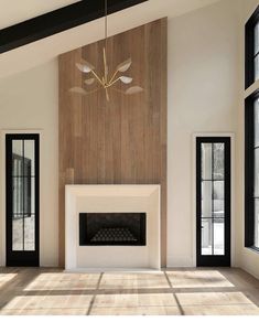 an empty living room with wood paneling and a fireplace in the center, surrounded by large windows