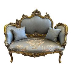 an ornately decorated couch with blue pillows on it's back and gold trimmings