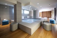 a large indoor swimming pool in the middle of a room with wooden floors and white walls