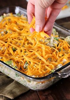 someone dipping cheese into a casserole dish with broccoli