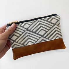 a hand is holding a zippered pouch that has a pattern on the front and sides