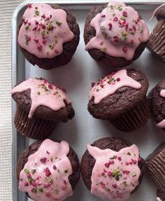 chocolate cupcakes with pink frosting and sprinkles in a tray