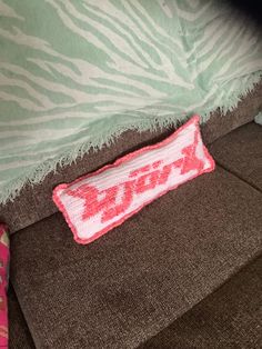 a pillow that is laying on top of a couch with the word love written on it