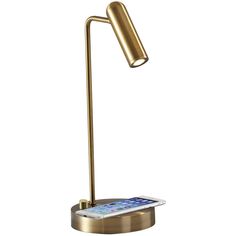 a gold desk lamp with an iphone on it's base and a white background