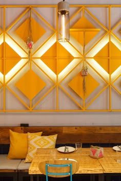 a wooden table topped with plates and bowls under a yellow wall mounted light hanging from the ceiling